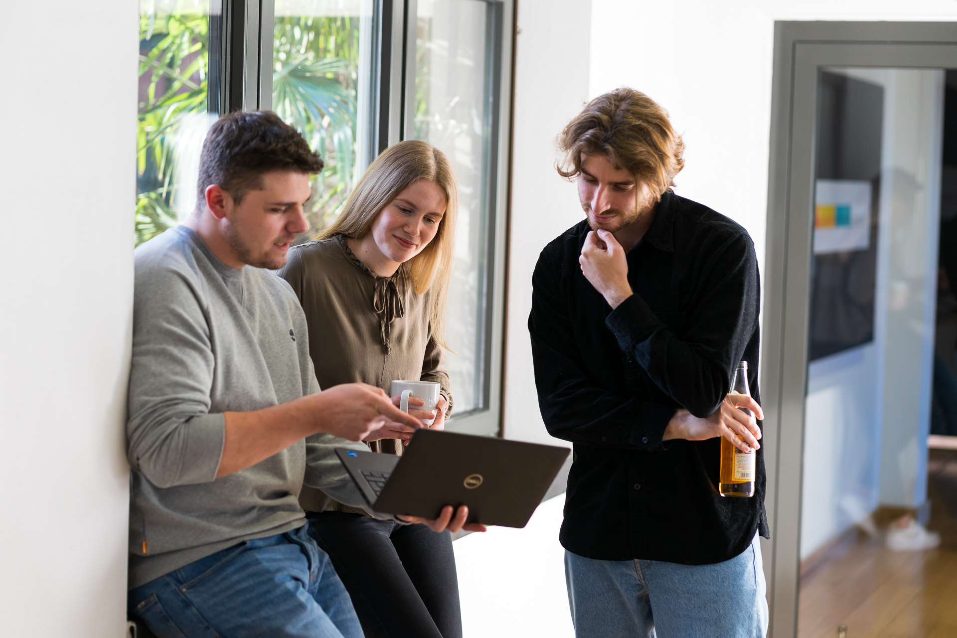 Foto von drei babiel Mitarbeitern die sich untereinander austauschen und gemeinsam auf einen Bildschirm schauen