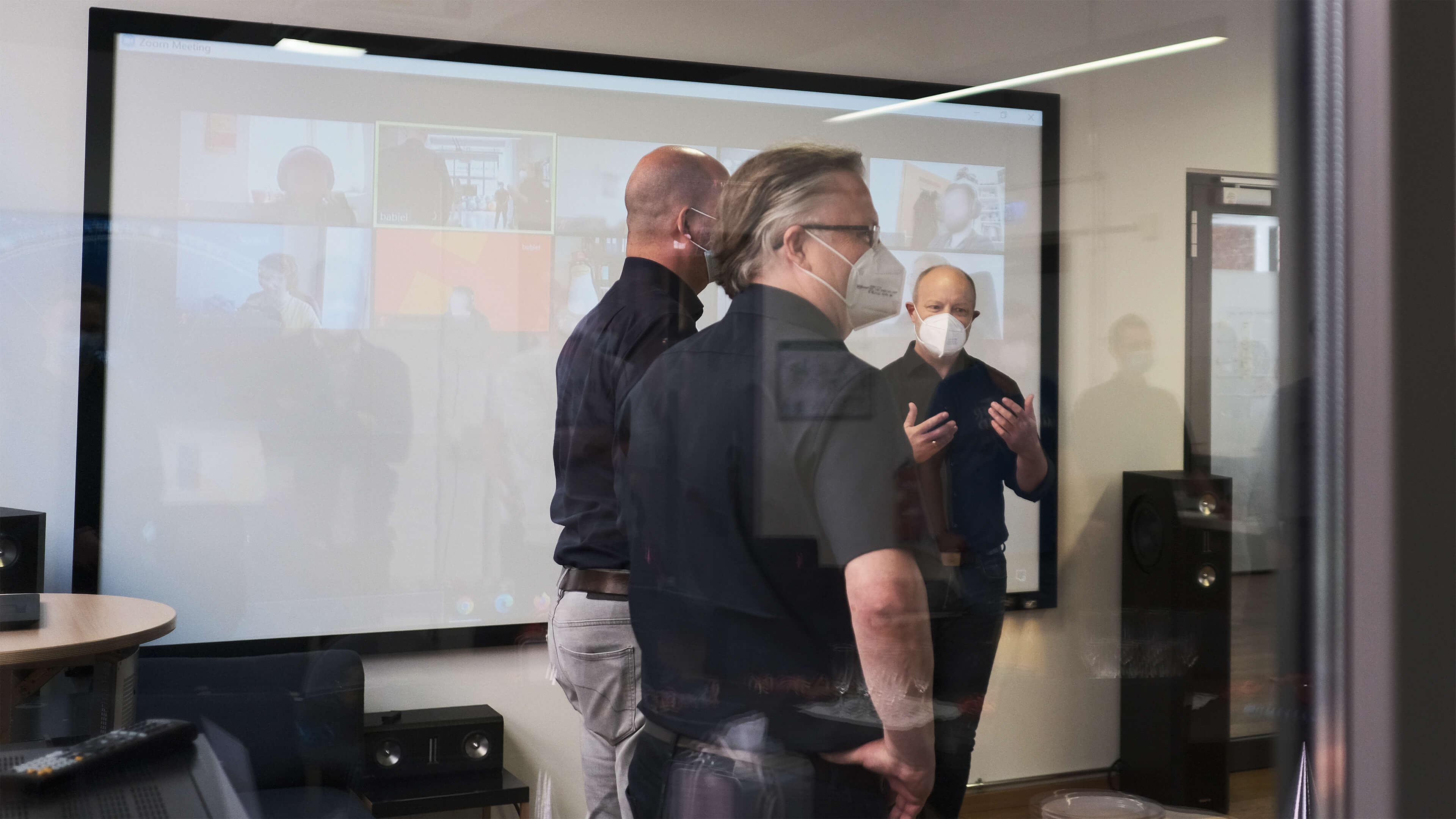 Foto zeigt ein babiel Büro mit einer Leinwand auf der eine Online Konferenz projiziert wird